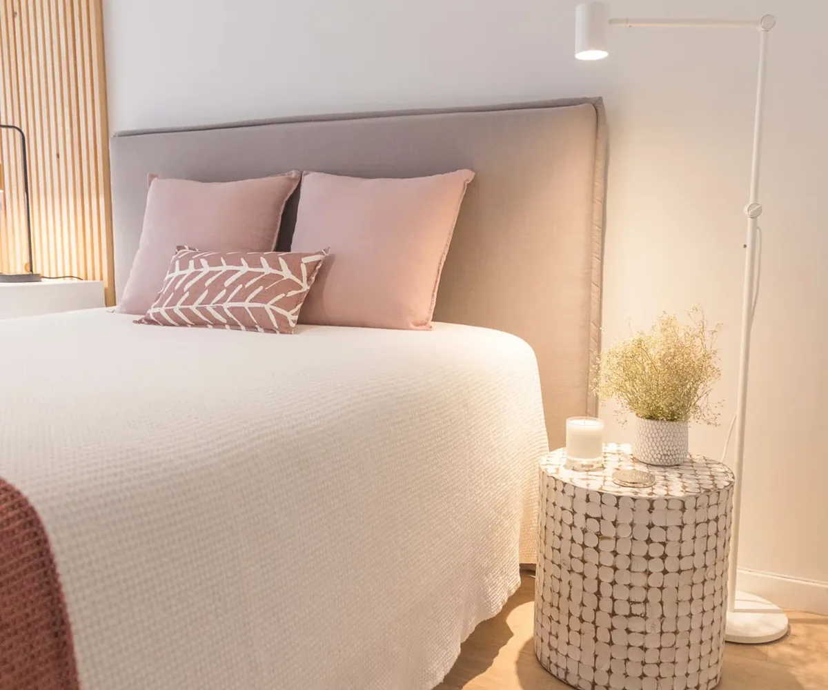 A neatly made white bed in an airy bedroom